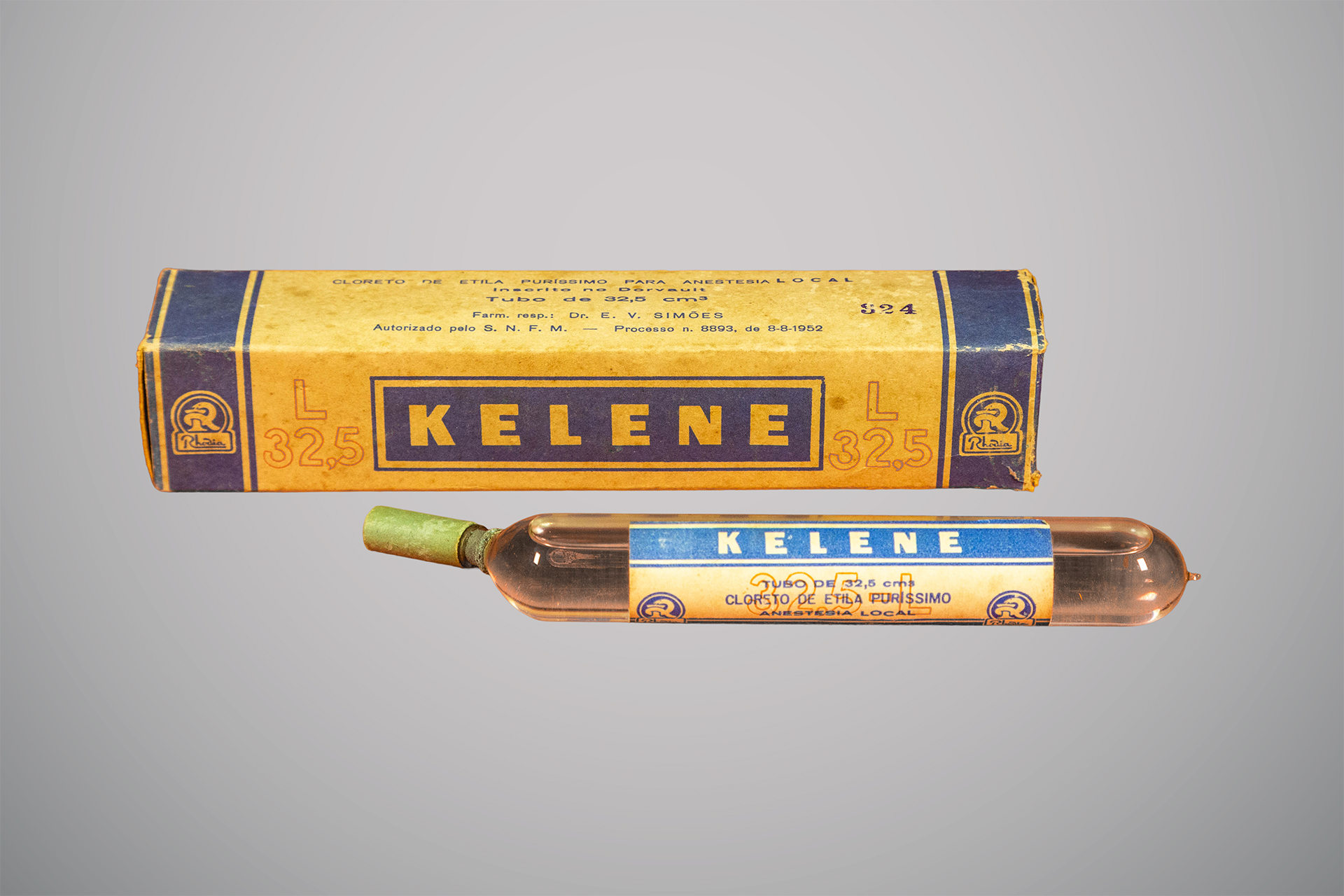 Caixa amarela e azul com a inscrição “Kelene” e um tubo de vidro transparente contendo cloreto de etila para anestesia local.