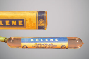 Caixa amarela e azul com a inscrição “Kelene” e um tubo de vidro transparente contendo cloreto de etila para anestesia local.