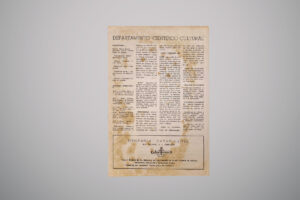 Fotografia de página única de boletim vista de frente, com título “Departamento Científico-Cultural” no topo e manchas de envelhecimento visíveis no papel. O texto está organizado em colunas e, ao final, há um anúncio publicitário da loja Dentária Catarinense em destaque.