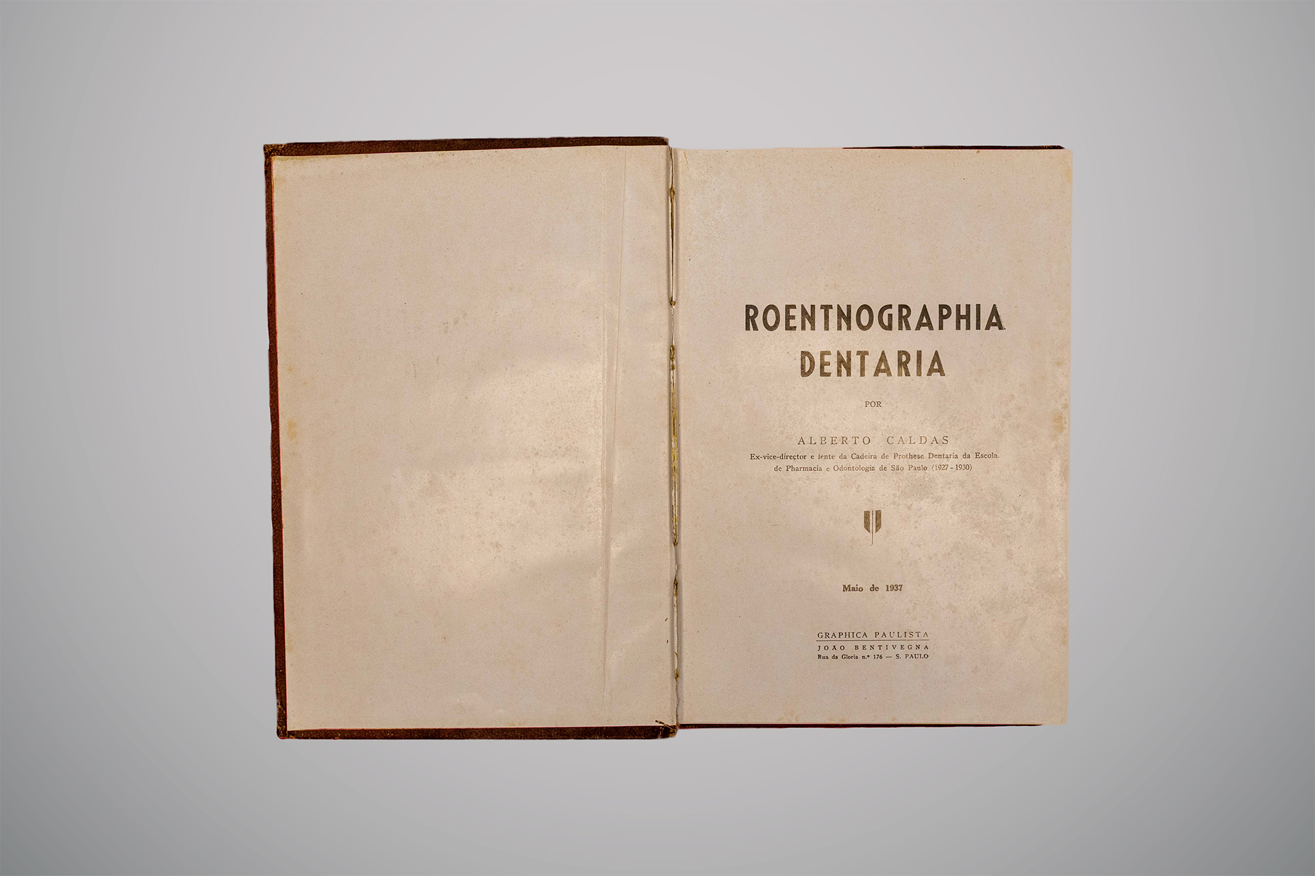 Página interna de livro antigo com fundo bege; à direita, há um retrato em tom sépia de um homem de barba cheia, identificado abaixo como "Wilhelm Conrad Röntgen".